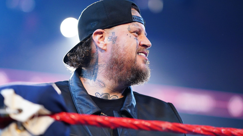Jelly Roll smiles as he peers over the top rope of a WWE ring.