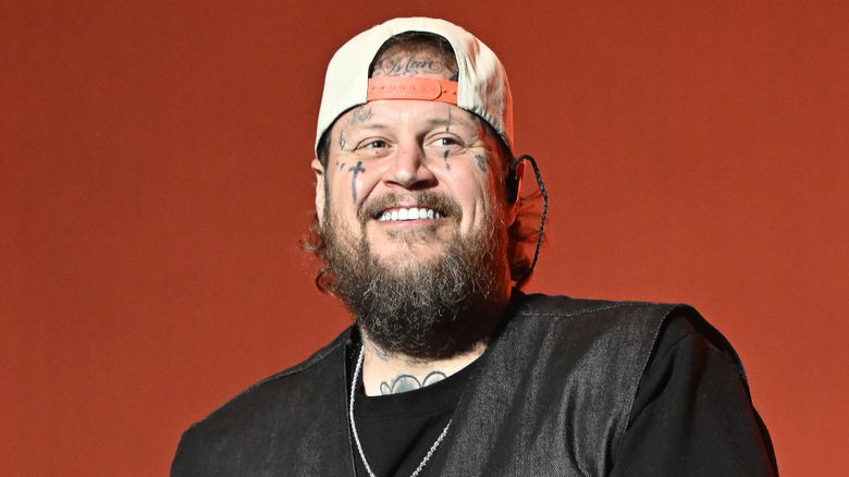 Jelly Roll smiling with a backwards cap on