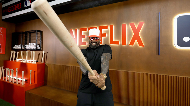 Jey Usos holding a baseball bat very close to the camera