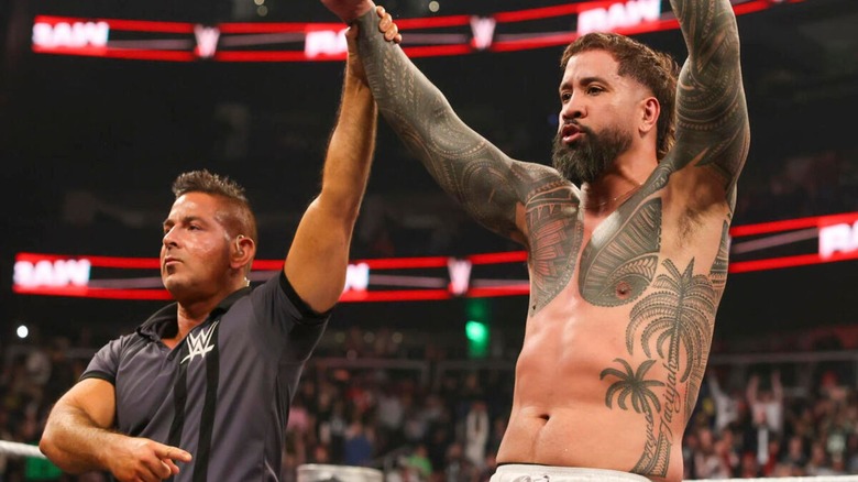 A referee holds up the arm of Jey Uso after a victory on an episode of 