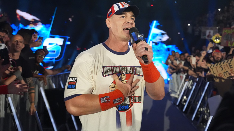 John Cena puts his hand on his heart as he speaks into the microphone amidst an engaged Lyon crowd.