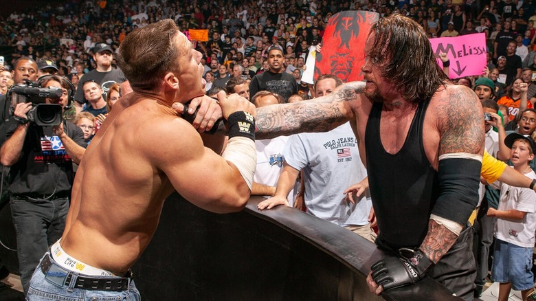 John Cena being grabbed by the throat by The Undertaker from behind the barrier in the crowd.