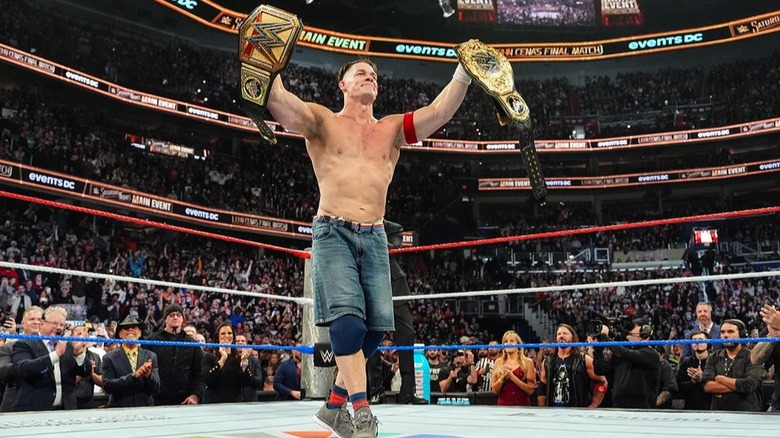 John Cena holds up the WWE World Heavyweight and Undisputed Championships minutes after concluding his last career match at Saturday Night's Main Event