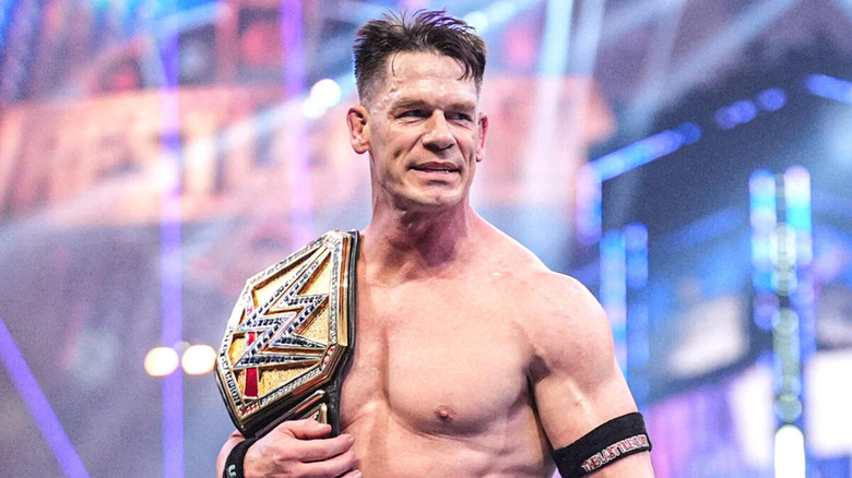 John Cena clenches his jaw as the WWE Universal Championship hangs on his shoulder.
