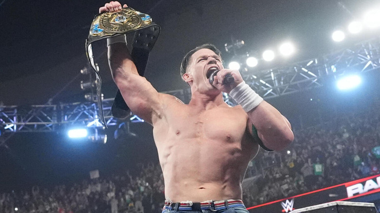 John Cena shouts into the microphone as he holds up the WWE Intercontinental Championship.