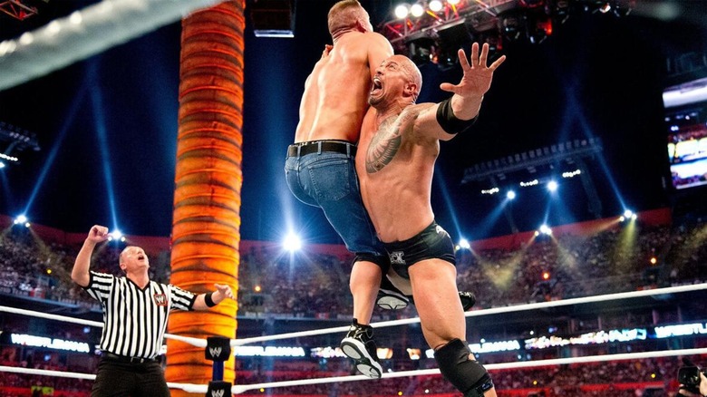 La roca golpea a John Cena con un fondo de roca durante WrestleMania 28.