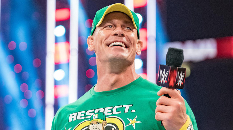 John Cena smiling while holding a WWE microphone