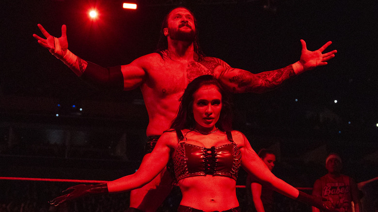 Karrion Kross, along with Scarlett, hit their signature pose before Kross competes in in-ring action