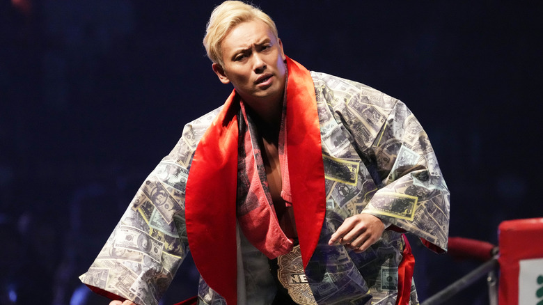 Okada making his entrance wearing his custom robe and the NEVER Championship in NJPW