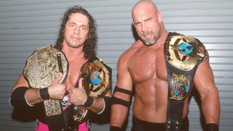 Bret Hart with the WCW World Heavyweight Championship and WCW Tag Team Championship alongside co-champion Goldberg in WCW.