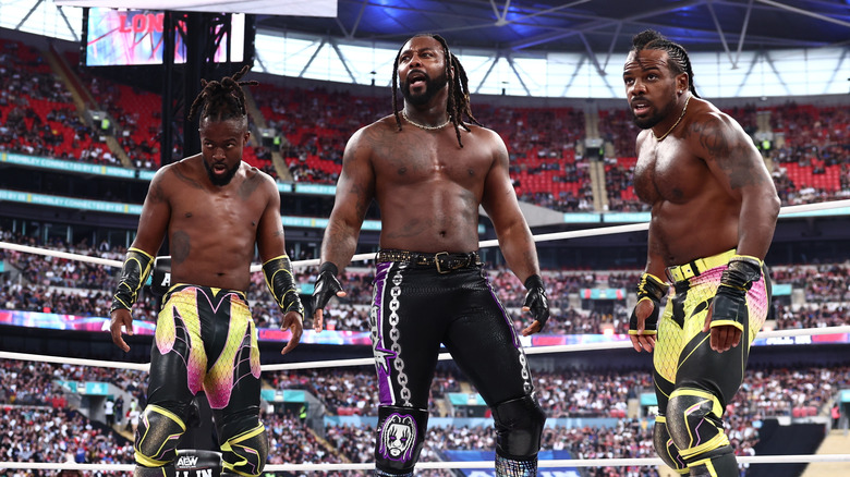 Kofi, Swerve Strickland, and Austin Creed stand in the ring, ready for battle, during the match for the AEW World Trios Championships at AEW All In: London.