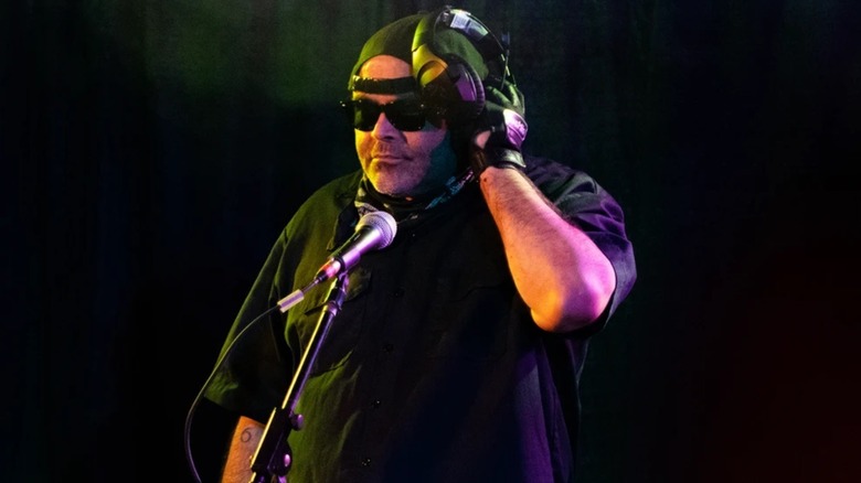 Konnan holds up headphones while DJing