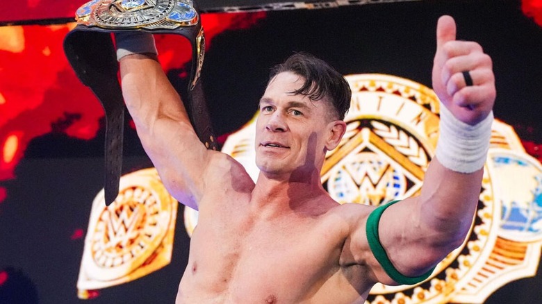 John Cena poses with the Intercontinental Championship on the stage following his victory over Dominik Mysterio on 