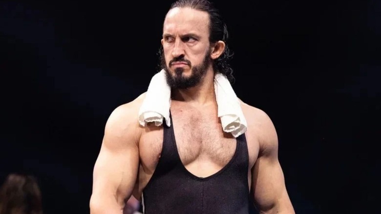 AEW star Pac, workout towel around his shoulders, heads down to the ring for a match on AEW programming.