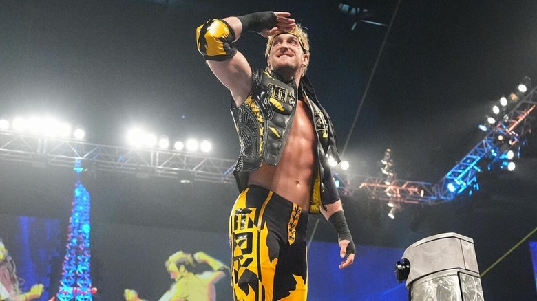 Logan Paul salutes toward the crowd while standing on the turnbuckle before a match against John Cena.