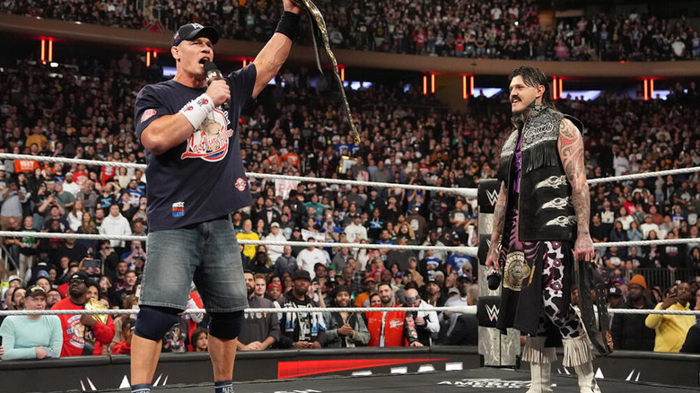 John Cena holds the IC title up in front of Dominik Mysterio