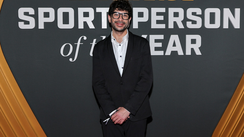 Tony Khan in front of a banner that reads Sports Illustrated Sportsperson of the Year