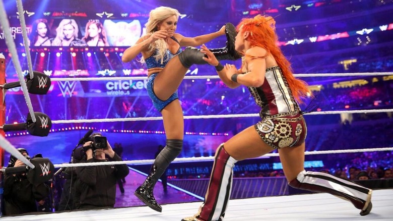 Charlotte Flair hits Becky Lynch with a big boot in the middle of the ring during their triple threat match at WrestleMania 32.