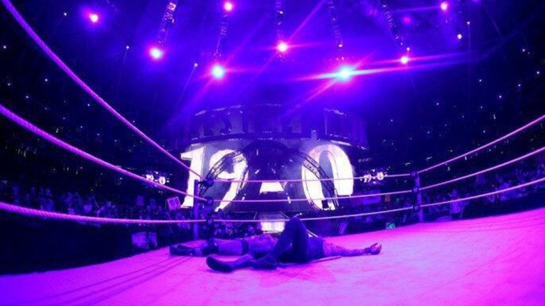 The Undertaker and Triple H lie in the ring, a 19-0 graphic on the tron behind them to honor Undertaker's undefeated WrestleMania streak, after their No Holds Barred match at 'Mania 27.