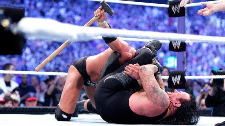 The Undertaker puts Triple H in the Hells Gate in the middle of the ring during their WrestleMania 27 match, but "The Game" holds on to a sledgehammer.