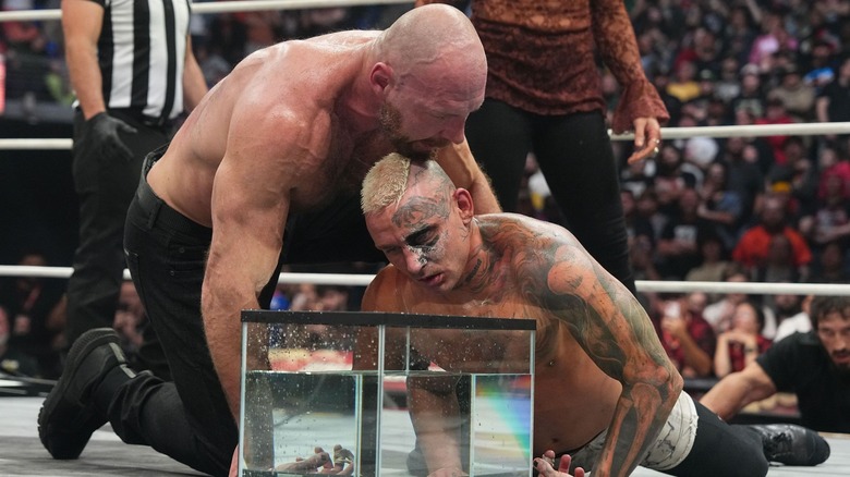 Jon Moxley pushing Darby Allin's head into a fish tank