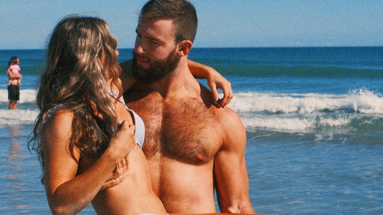Cutler James holds Adriana Rizzo in his arms as they look lovingly at each other in a photo taken on the beach.