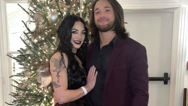 Tatum Paxley and Javier Bernal pose in front of a Christmas tree.