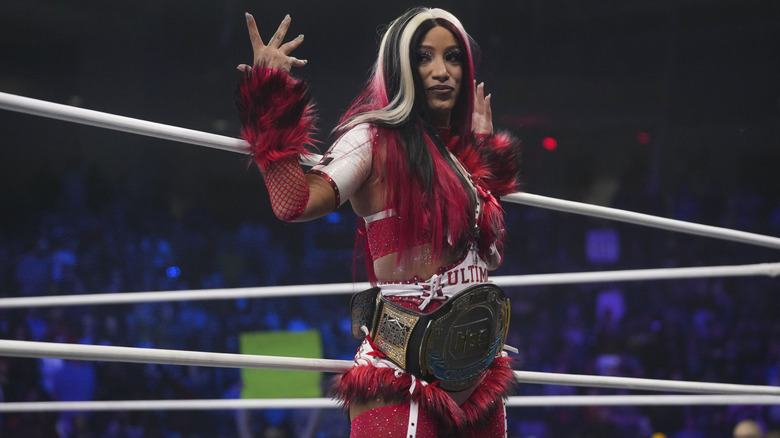Then-TBS Champion Mercedes Mone poses on the ring apron, the belt around her waist, before a match on the December 31, 2025 edition of 