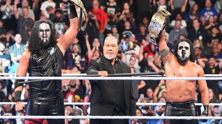 Haku stands in between his sons, the MFTs, Talla Tonga and Tonga Loa, who hold the WWE Tag Team Championships aloft after a victory on 