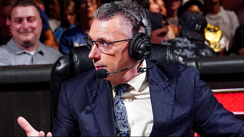Michael Cole confirms an announcement at the broadcasting table
