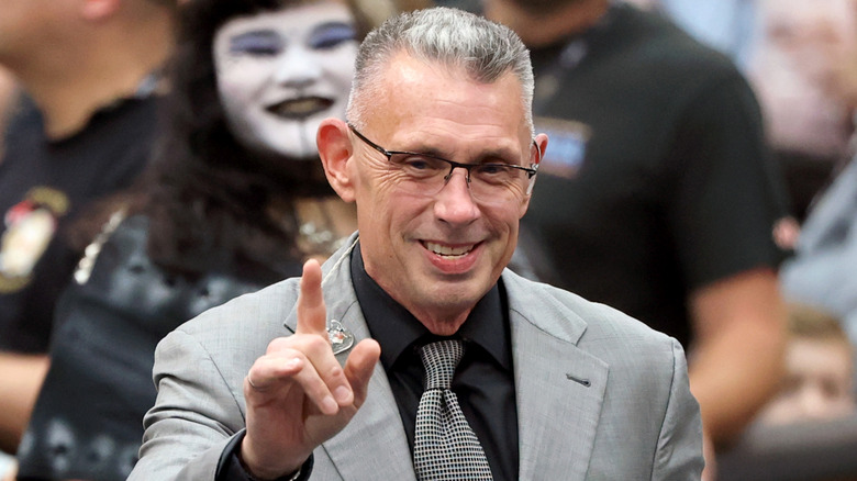 Michael Cole smiling and pointing up