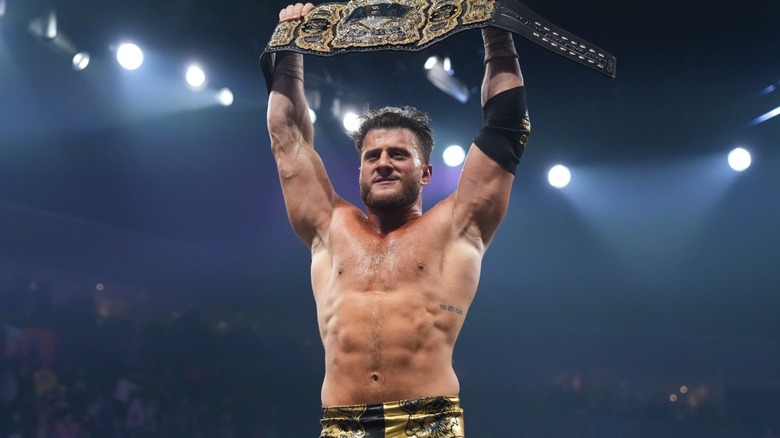 MJF holding the AEW World Championship above his head in triumph after winning the belt at AEW Worlds End 2025.