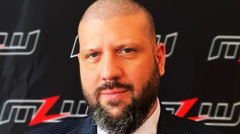 Major League Wrestling executive Court Bauer poses for a camera in front of a MLW backdrop.