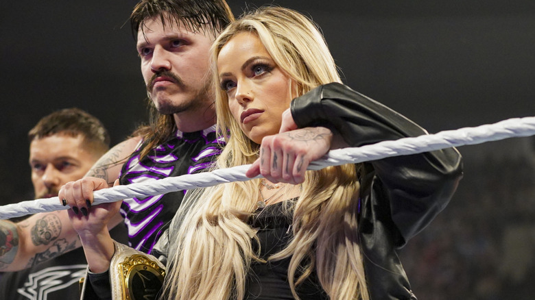 Liv Morgan standing in the ring with Dominik Mysterio and Finn Balor
