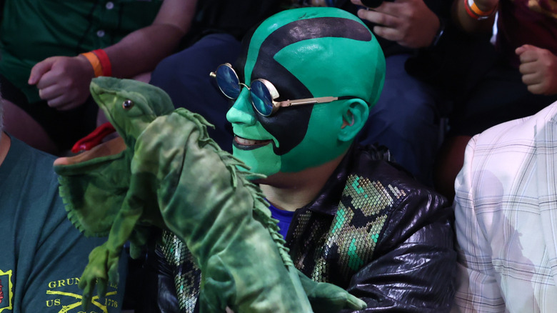 Mr. Iguana sitting in the crowd at a WWE event holding La Yezca