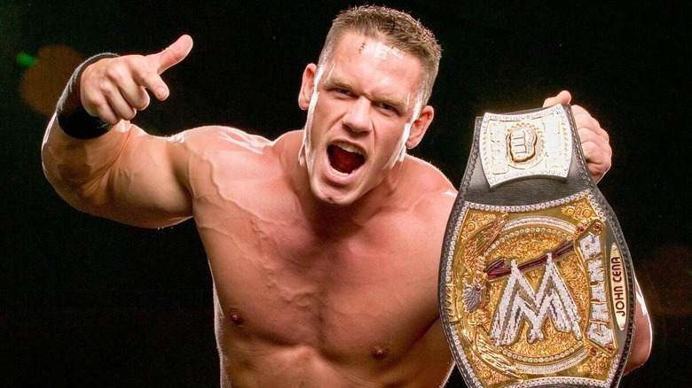 John Cena posing with the WWE Championship during a photoshoot.