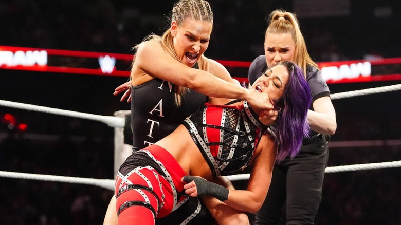 Nattie puts Bayley in a submission hold in the middle of the ring as referee Jessika Carr looks on during a match on 