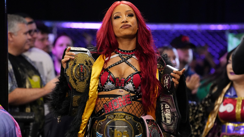 Mercedes Mone poses with her belts on her way to the ring during an episode of 