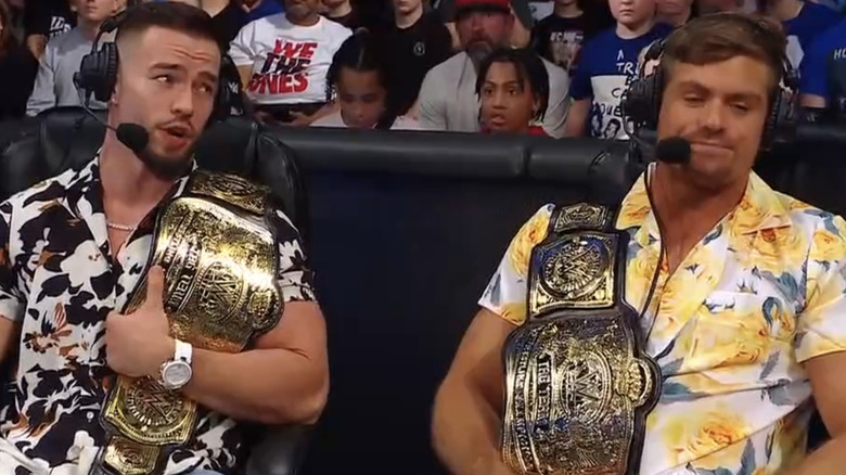 Austin Theory and Grayson Waller sit on commentary with the new WWE Tag Team Championships.