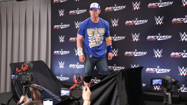 John Cena standing behind a broken table with R-Truth lying nearby