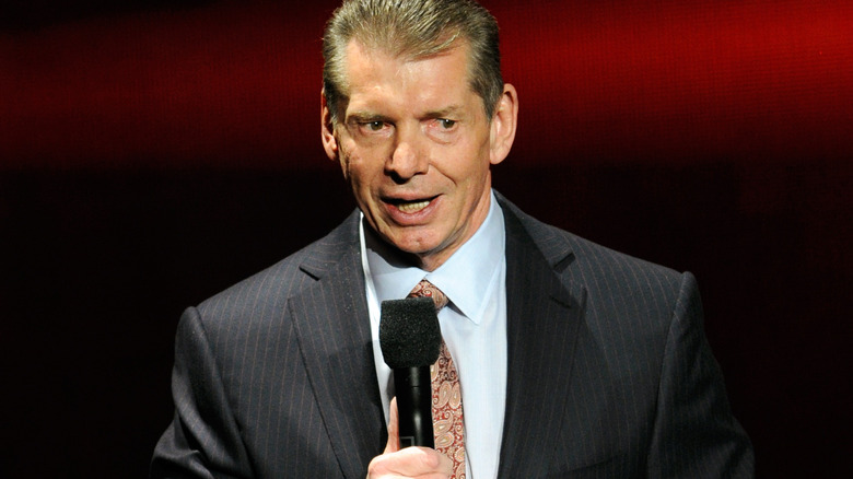 Vince McMahon is holding a microphone