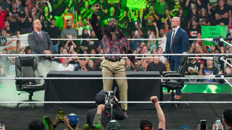 Oba Femi poses in the ring, Paul Heyman and Paul 