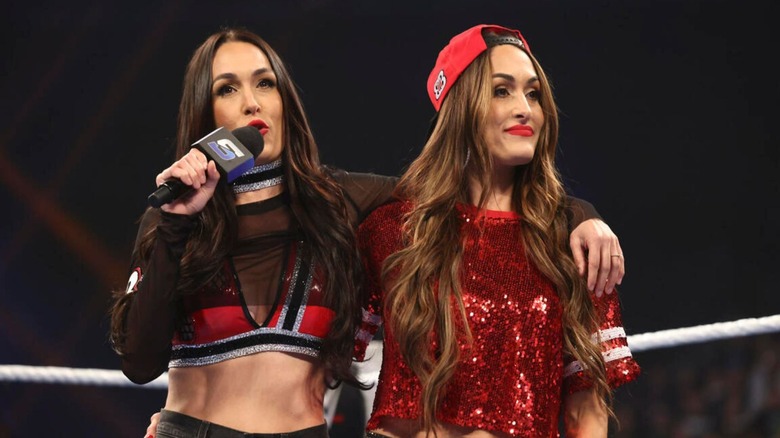 Brie Bella cuts a promo on Charlotte Flair and Alexa Bliss, her arm around twin sister, Nikki, during an episode of 