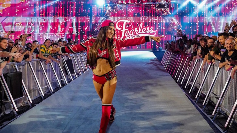 Nikki Bella points toward the fans as she heads down the ramp to the ring for a match on WWE programming.