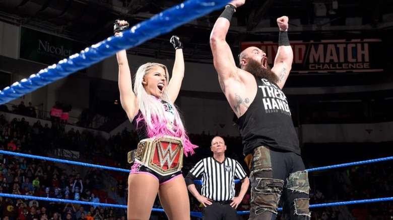 "WWE Raw" Women's Champion Alexa Bliss and Mixed Match Challenge partner Braun Strowman raise their arms in the middle of the ring and pose for the audience before a match.