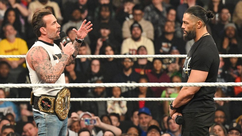 Roman Reigns stares at CM Punk in the ring as he cuts a promo during their main event segment on 