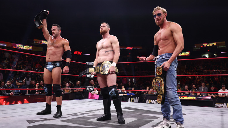 Roderick Strong, Kyle O'Reilly, and Orange Cassidy pose with the AEW World Trios Championships in the ring after a match on 