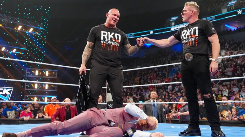 Randy Orton and Pat McAfee fist bump after annihilating Cody Rhodes, who's laying on the mat