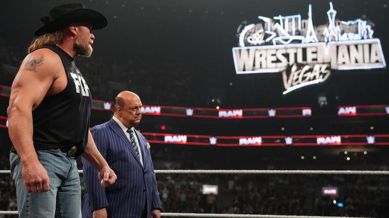 Paul Heyman, with his client, Brock Lesnar, stand in the middle of the "WWE Raw" ring with the WrestleMania 42 neon light looming in the distance
