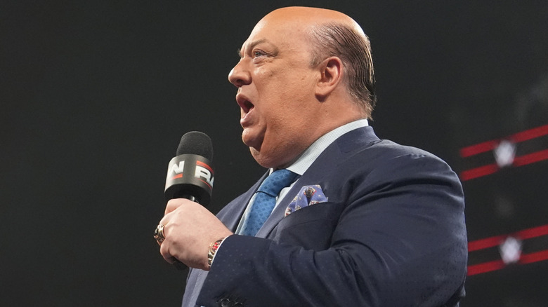 Side profile of Paul Heyman holding a WWE Raw microphone